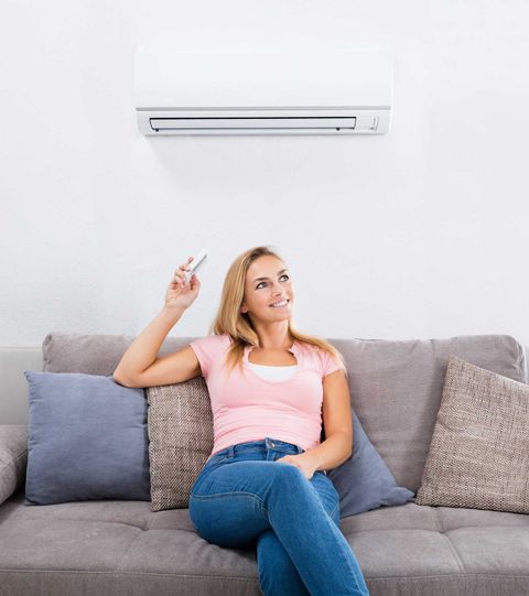 Woman Sitting on Couch Below Air Conditioner