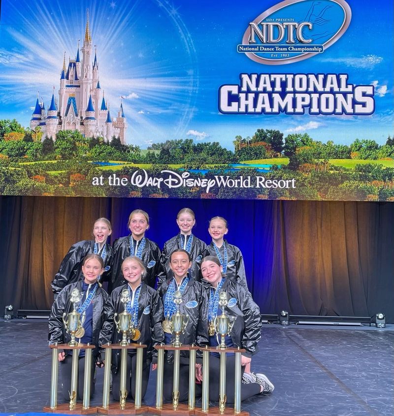 A group of young girls are posing for a picture in front of a sign that says national champions