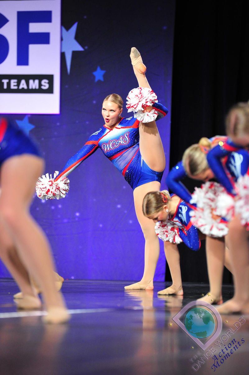 A group of cheerleaders are performing on a stage in front of a sign that says sf teams