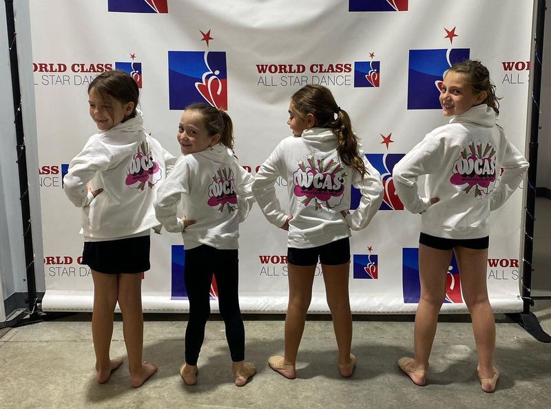A group of young girls standing in front of a wall that says would class