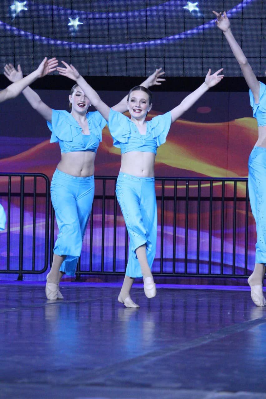 A group of women in blue outfits are dancing on a stage