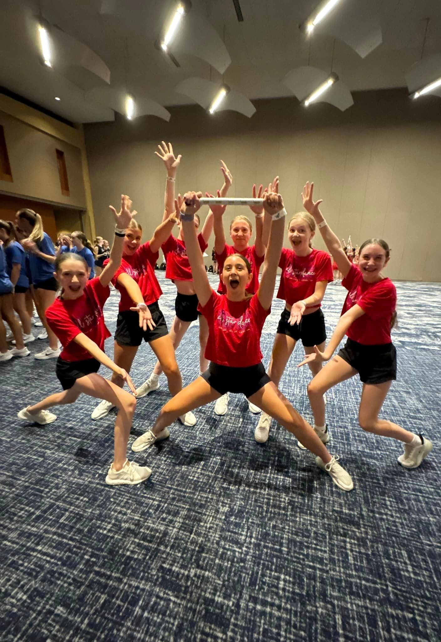 A group of young girls are posing for a picture in a room.