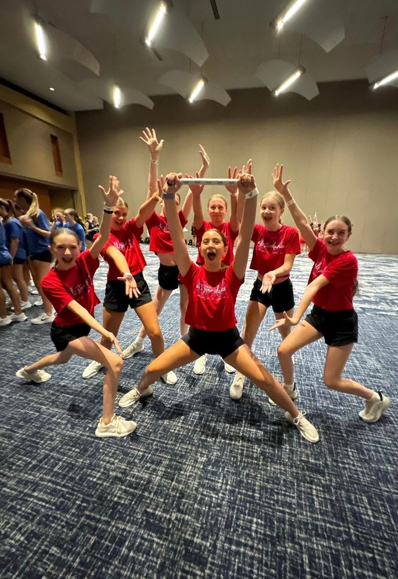 A group of young girls are posing for a picture in a room.