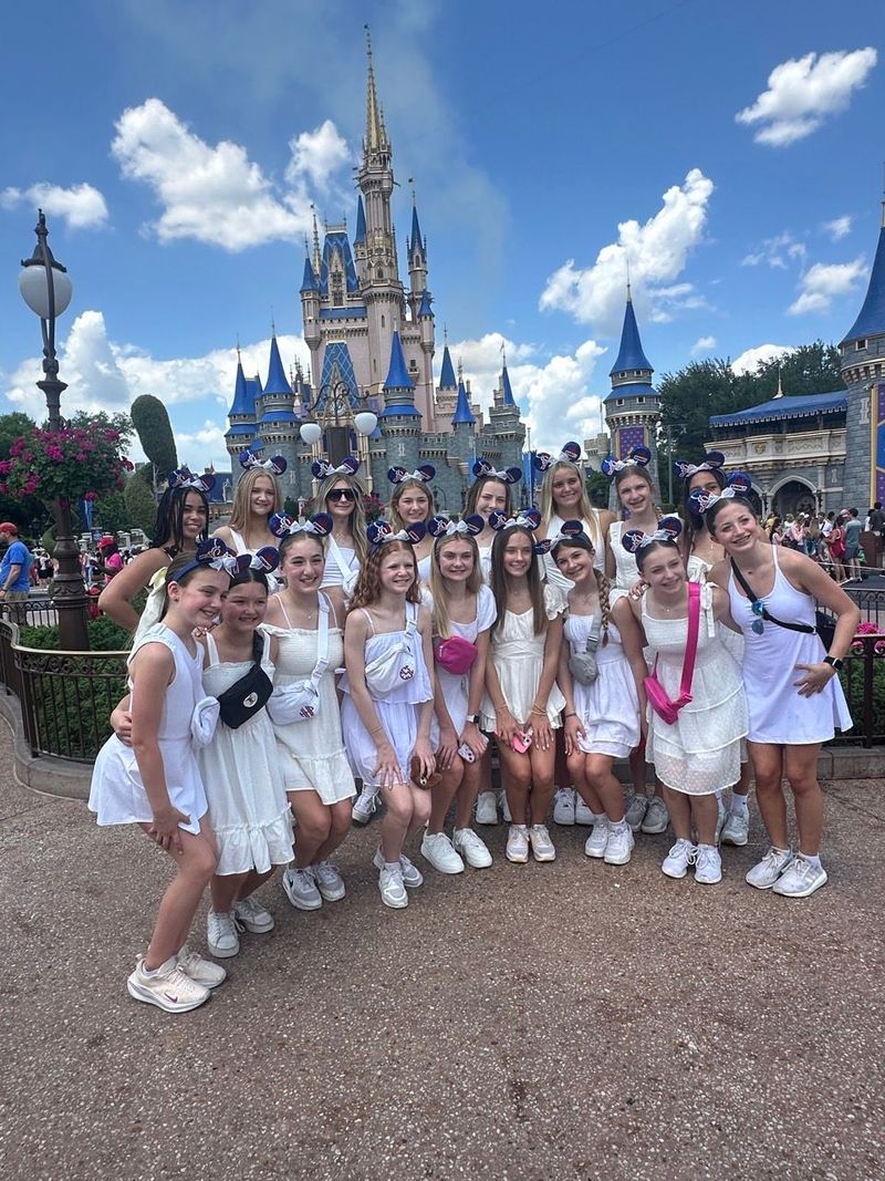 A group of girls are posing for a picture in front of a castle.