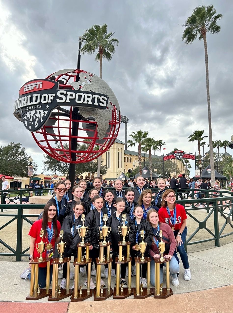A group of people are posing for a picture with trophies in front of a world of sports sign.