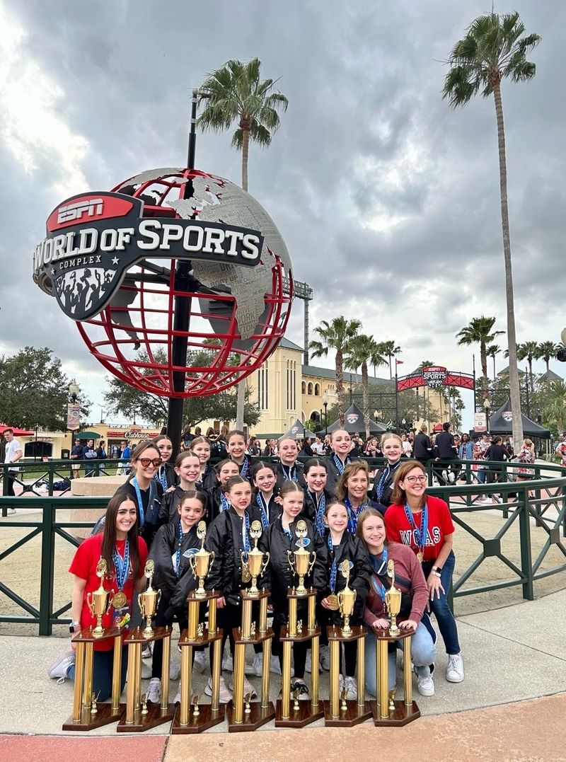 A group of people are posing for a picture with trophies in front of a world of sports sign.