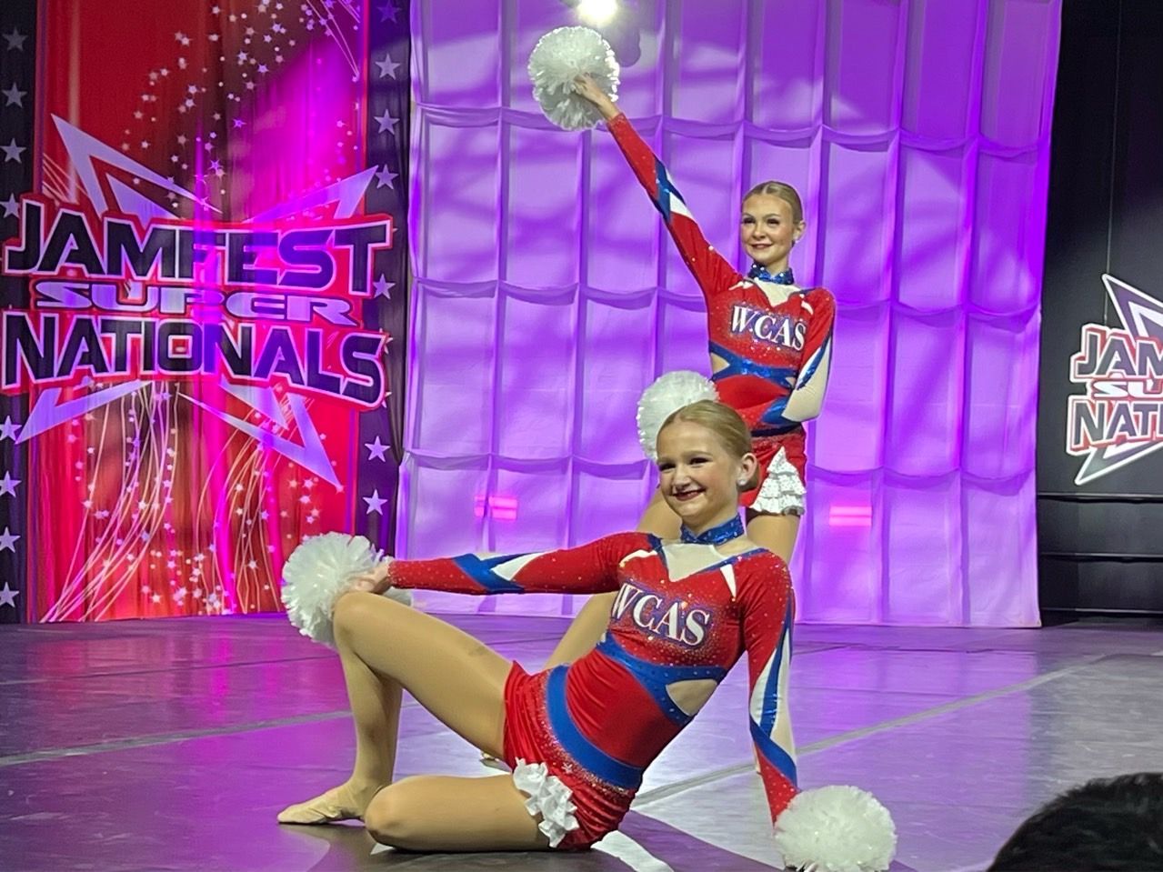 Two cheerleaders are performing on stage at the jamfest of the nationals
