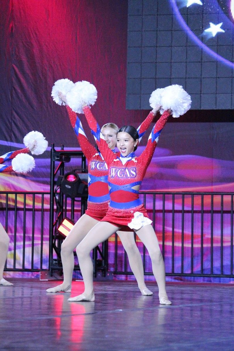 The cheerleaders are wearing texas uniforms and holding pom poms in the air