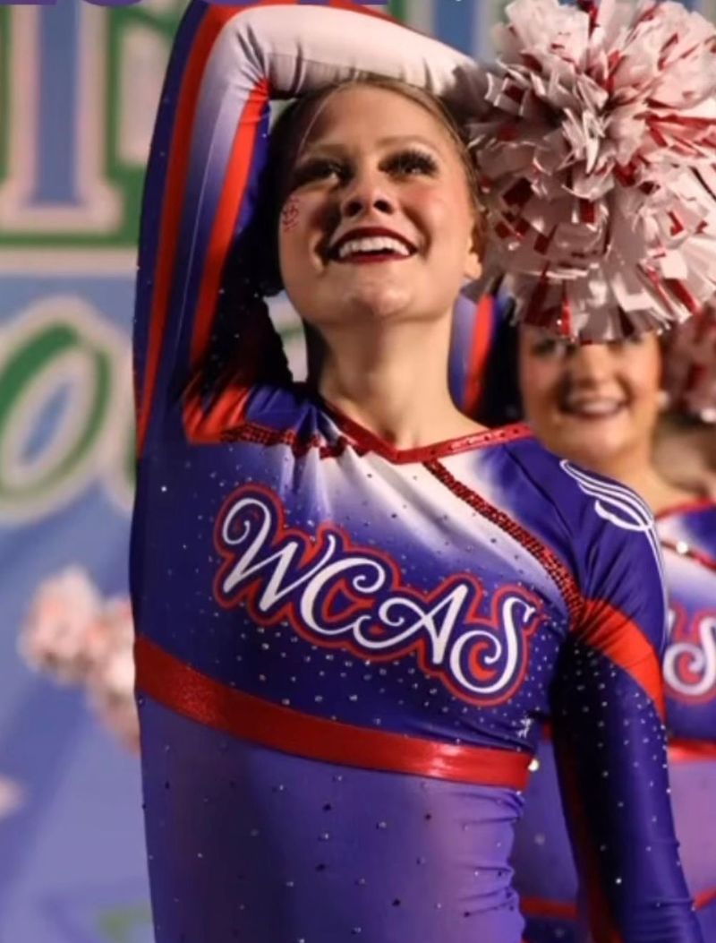 A cheerleader wearing a purple shirt that says wcas