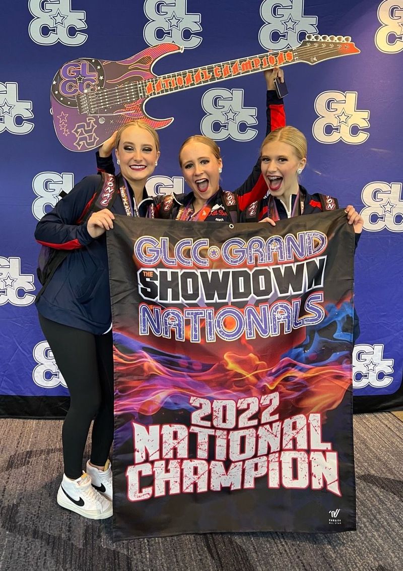 Three girls are holding a sign that says 2022 national champion
