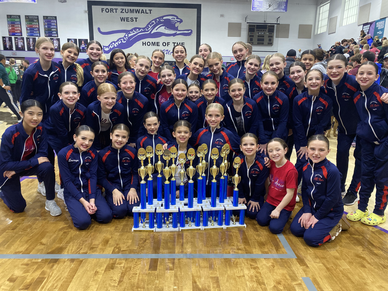 A group of young girls are posing for a picture with trophies