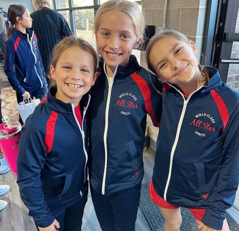 Three young girls wearing all star jackets are posing for a picture