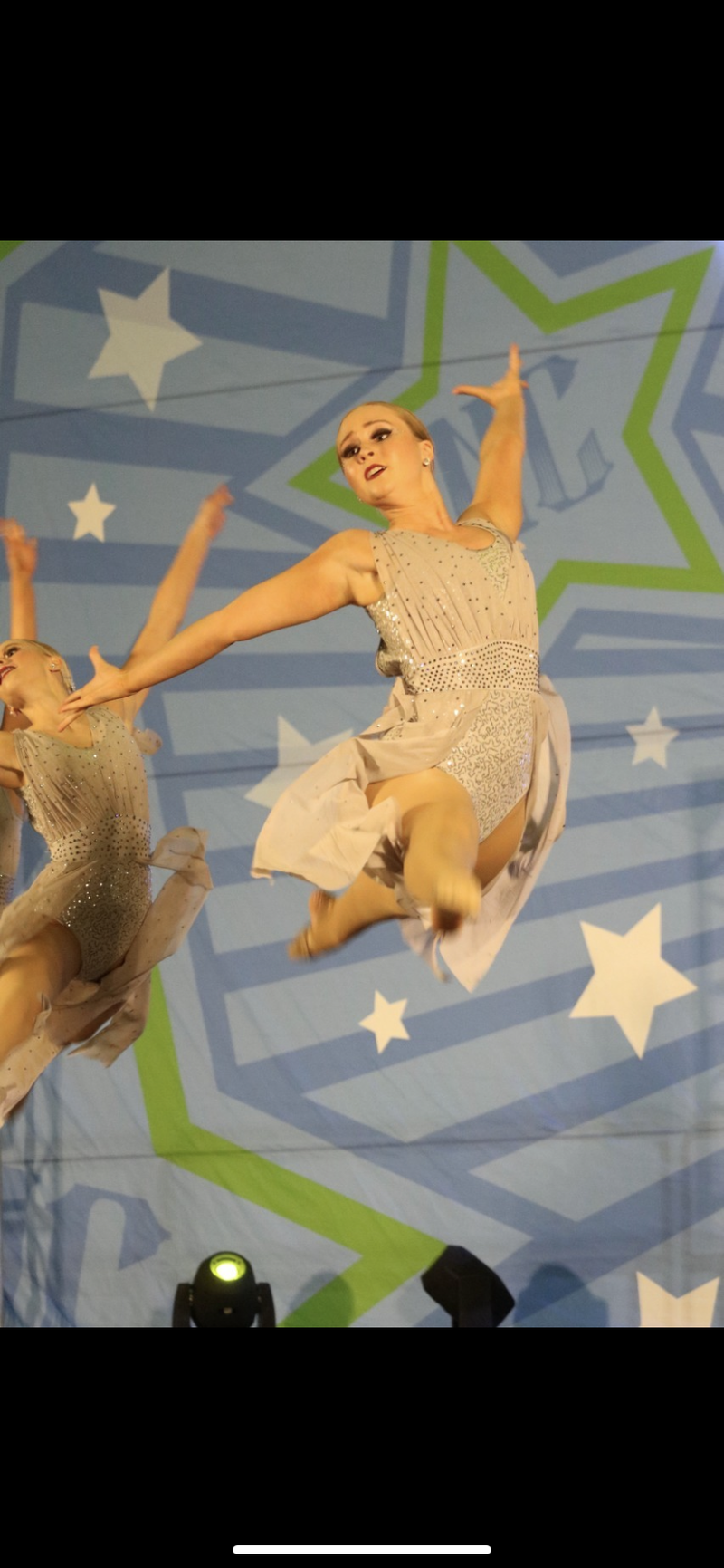 A group of dancers are jumping in the air on a stage.