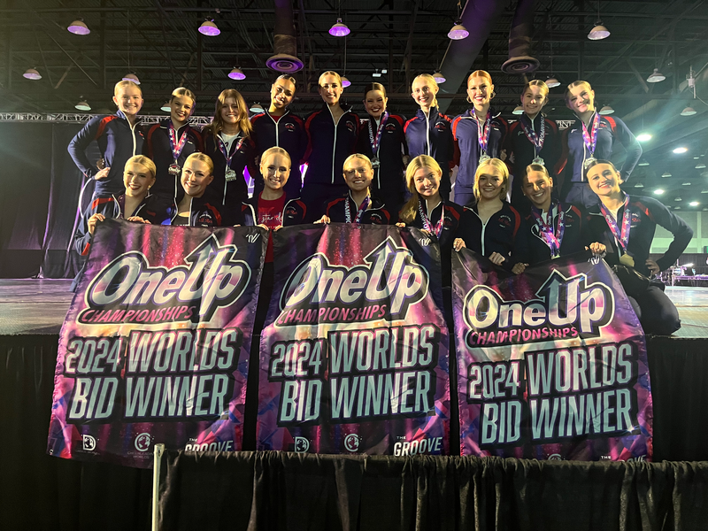 A group of people standing on a stage holding signs that say 2024 worlds bid winner.