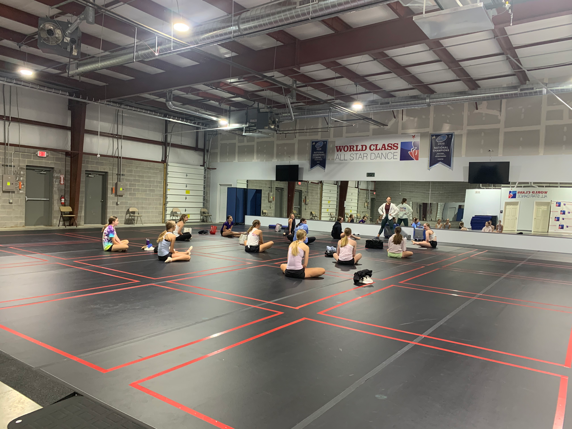 A group of people are sitting on the floor in a gym.