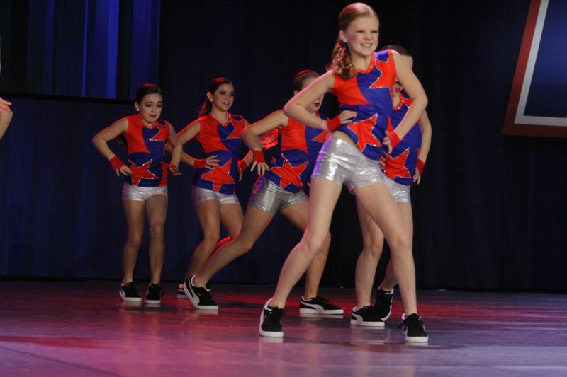 A group of young girls are dancing on a stage.