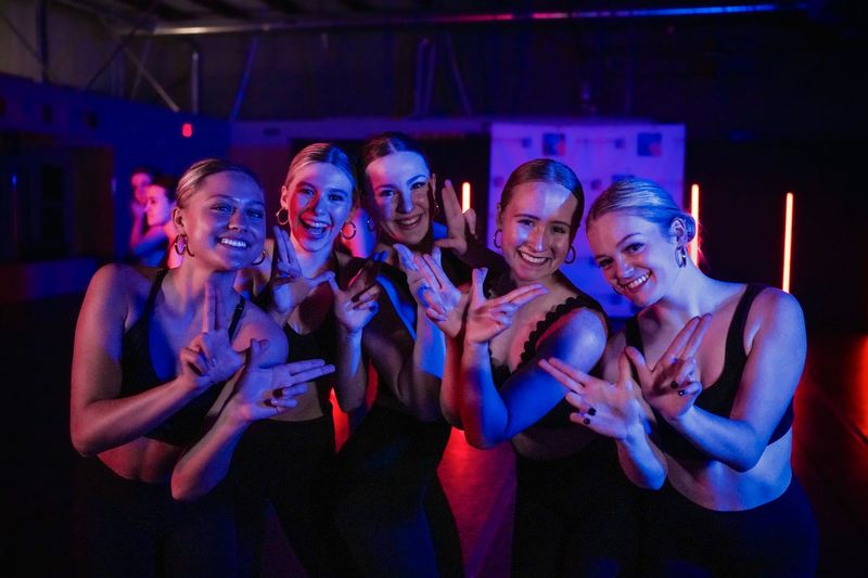 A group of young women are posing for a picture in a dark room.