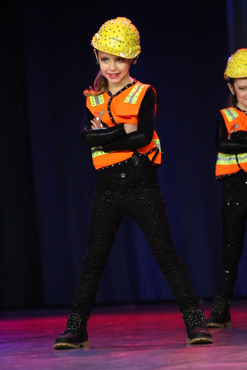A girl wearing a hard hat and an orange vest