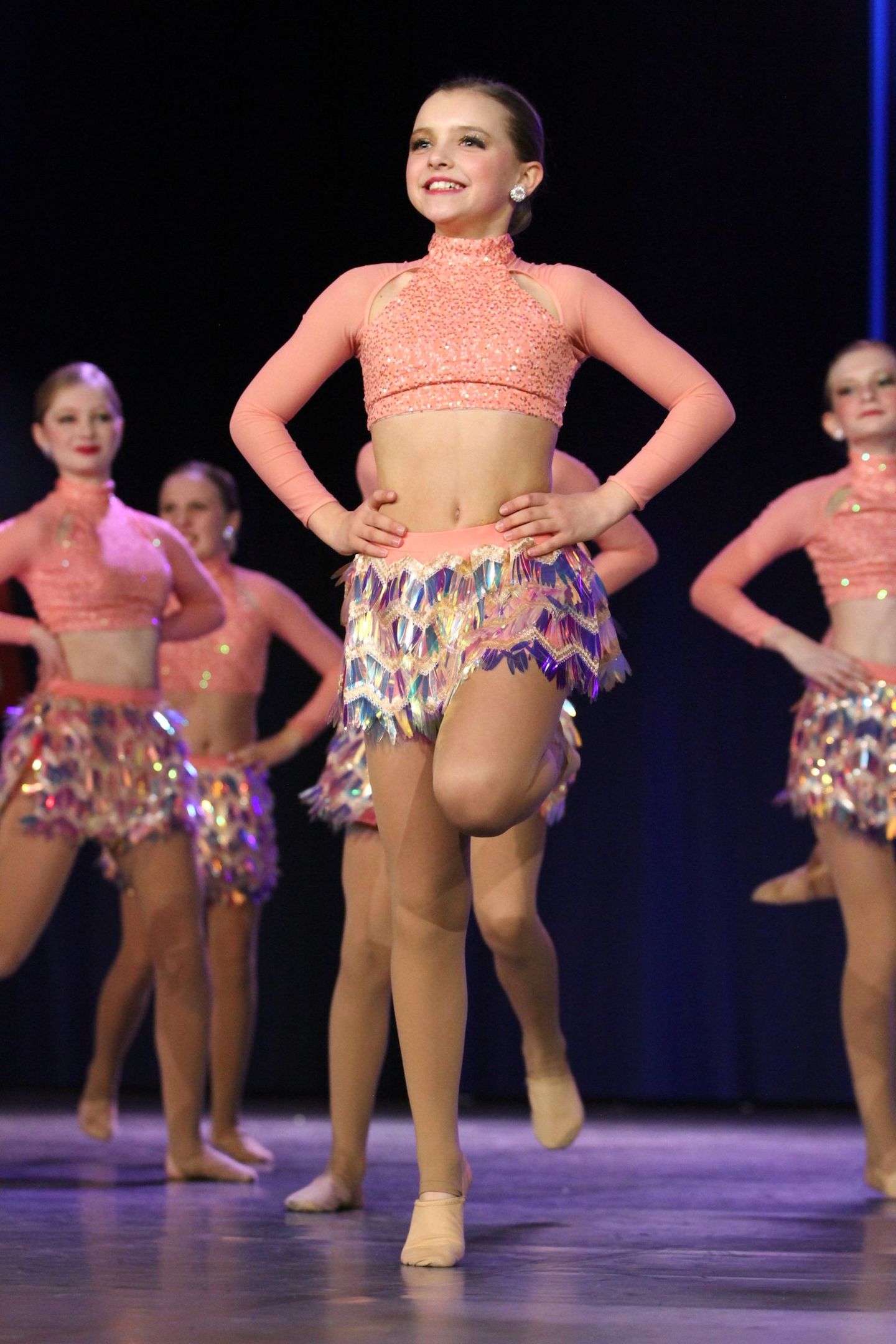 A group of young girls are dancing on a stage.