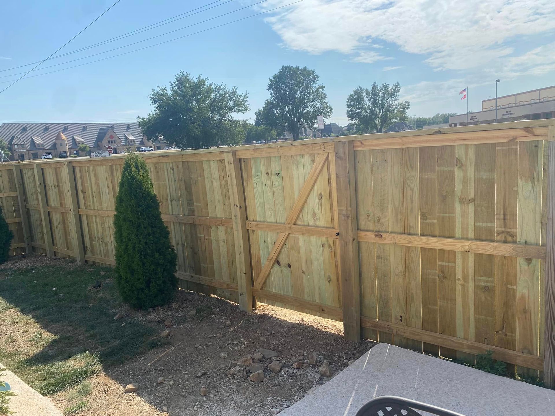Wooden fence with gate in yard, bright sunny day.