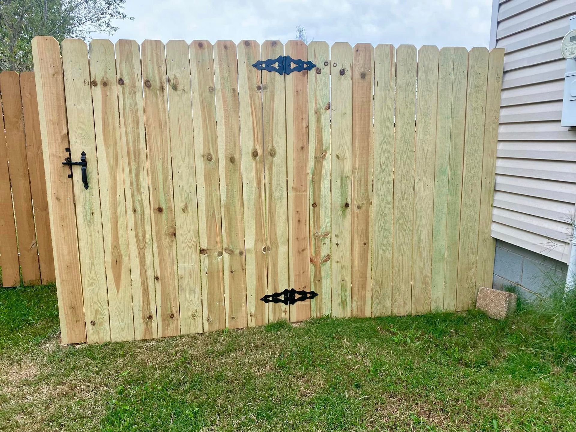 Woman in straw hat smiles, holding wine glass near a lake.