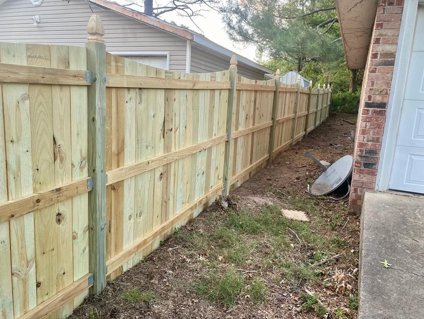 Wooden fence in backyard, built next to brick house.