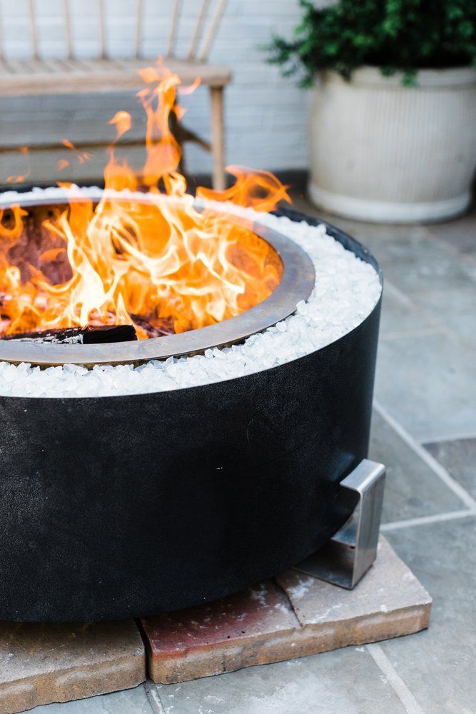 Two light-colored Adirondack chairs with a shared table sit on a lush lawn near a metal armillary sphere garden ornament.