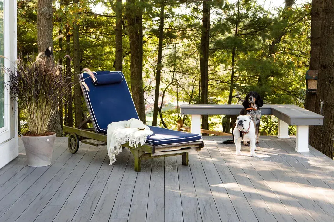 Two light-colored Adirondack chairs with a shared table sit on a lush lawn near a metal armillary sphere garden ornament.