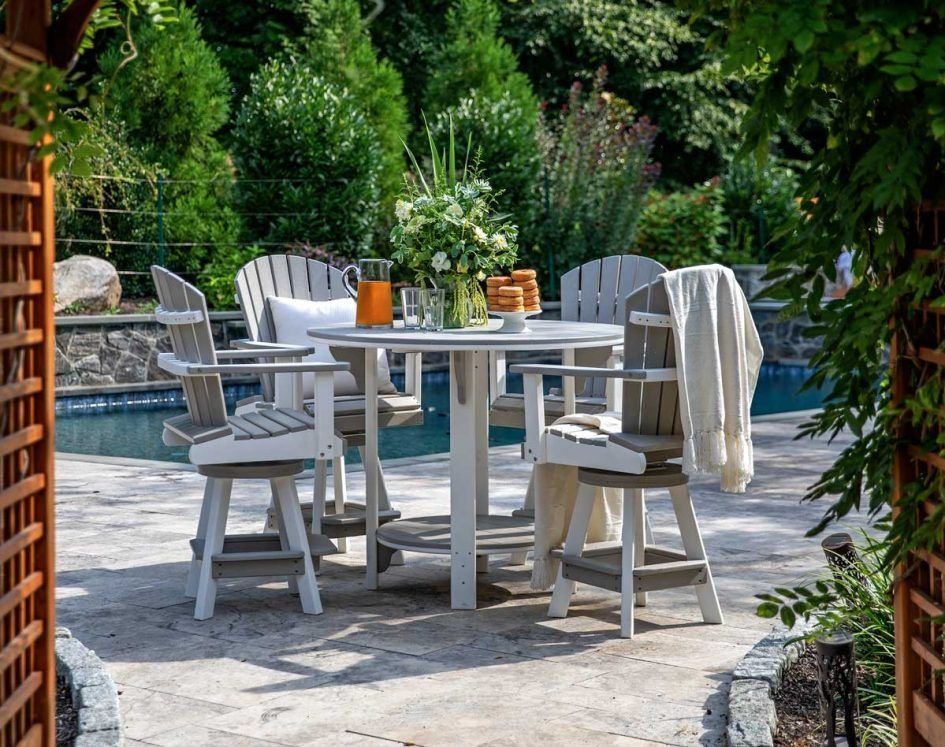 A showroom display with a light-colored outdoor sofa, fire pit, and dining set against a backdrop of siding samples.