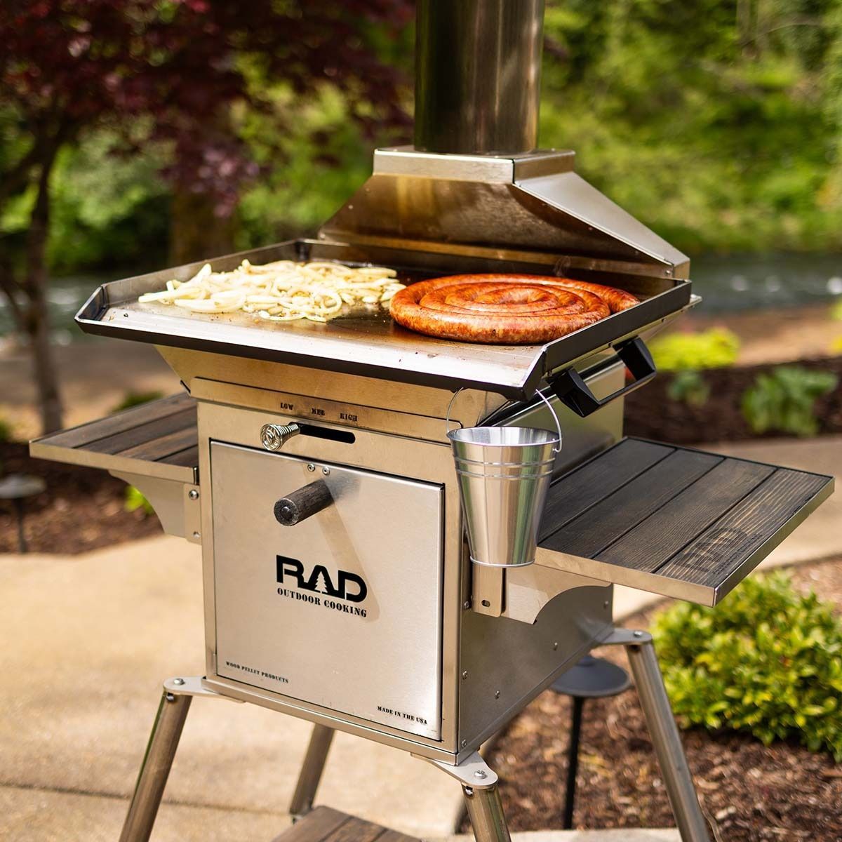 Outdoor stainless steel grill with pizza and food cooking on the grates, on a patio.