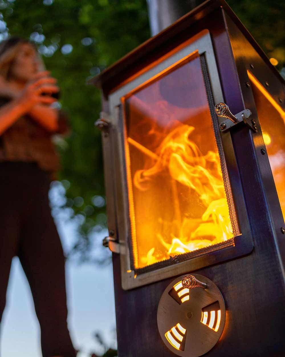Two light-colored Adirondack chairs with a shared table sit on a lush lawn near a metal armillary sphere garden ornament.