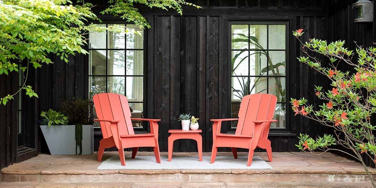 Outdoor patio table set beside a blue pool, surrounded by wooden chairs and lush greenery
