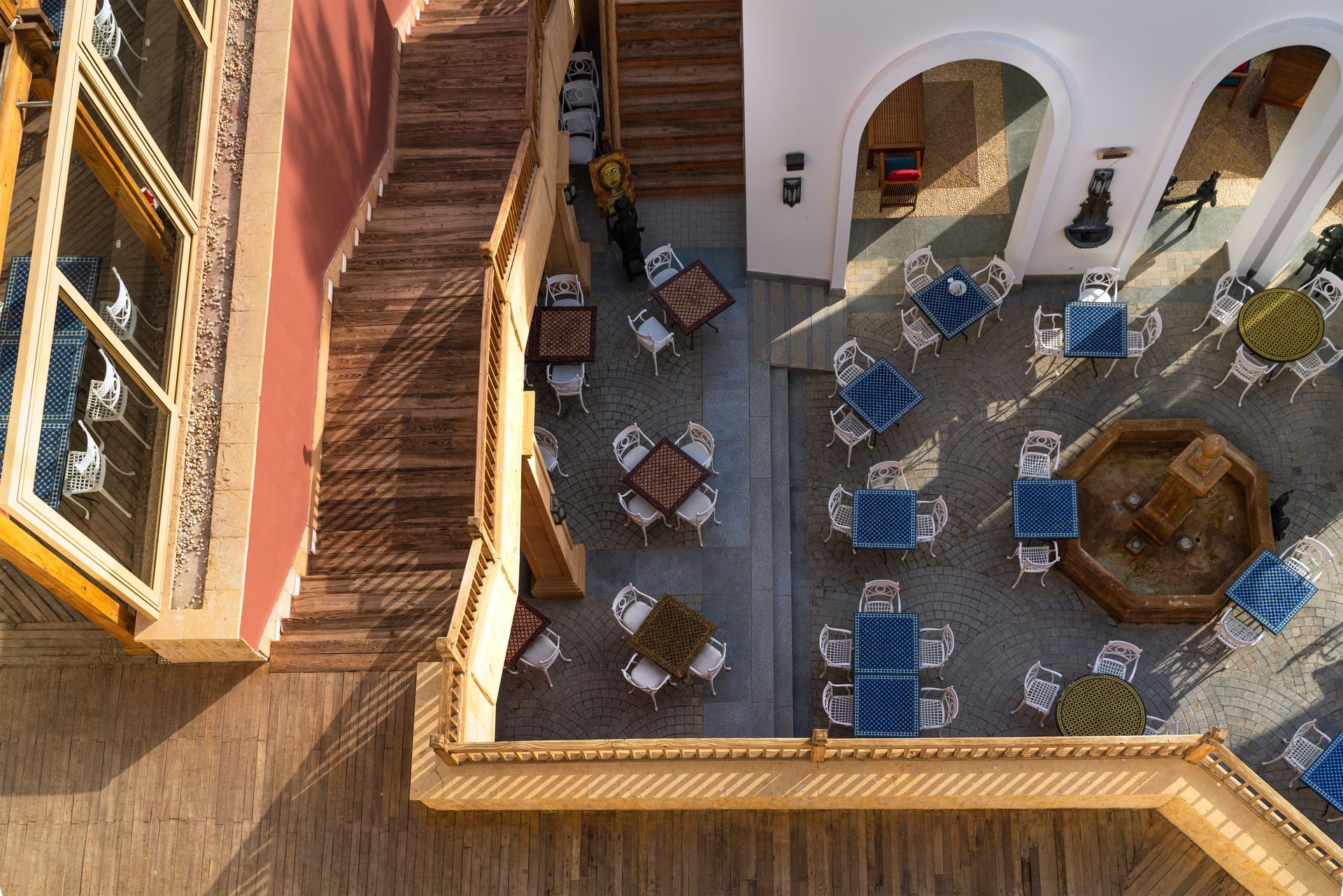A smiling person with dark hair, wearing a red cable-knit sweater against a neutral, paneled wall background.