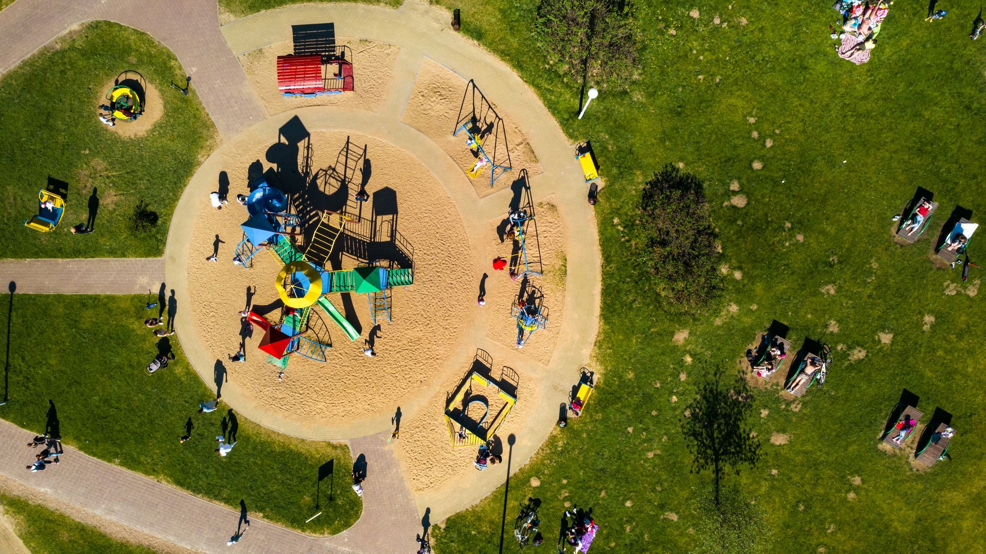 A smiling person with dark hair, wearing a red cable-knit sweater against a neutral, paneled wall background.