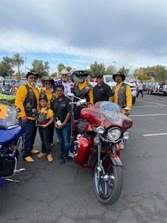 Group of people with a red motorcycle posing in a parking lot under a cloudy sky.