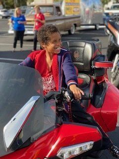 Young person smiling while sitting on a red motorcycle.