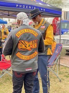 Two men wearing motorcycle club jackets, one reading 