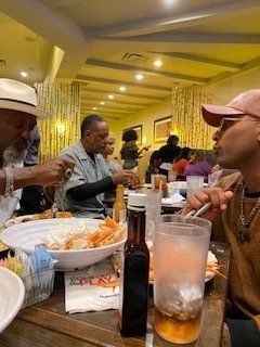 People eating at a restaurant. A large bowl of food sits on the table. Warm lighting.