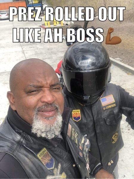 Two men in leather jackets and helmets on a motorcycle. One is taking a selfie with the other. Text above says 