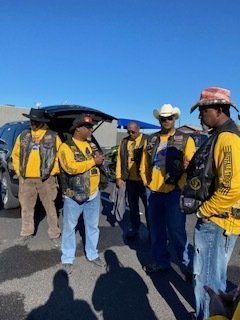 Group of people wearing yellow shirts and vests outside a vehicle, discussing.