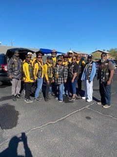 Group of people in vests posing outdoors on a sunny day.
