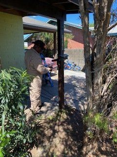 Person in a jumpsuit working on a metal post outdoors under a covered structure.