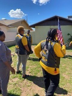 Group of people in yellow shirts and vests outside holding an American flag.