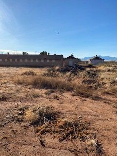 Desert landscape with abandoned brick buildings under a blue sky.