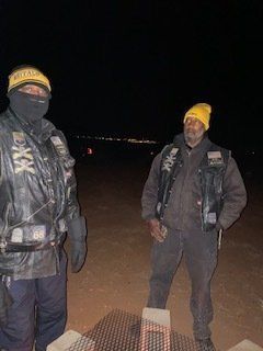Two people in biker gear at night. One wears a balaclava. Both have yellow hats and patches.