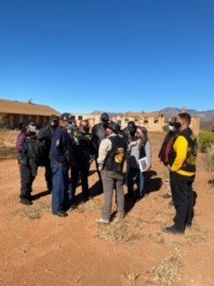 A group of people standing outside a dilapidated building on a sunny day.