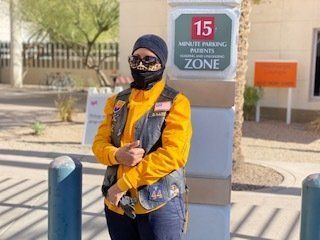 Person in biker gear, face mask, by a 15-minute parking sign outside.