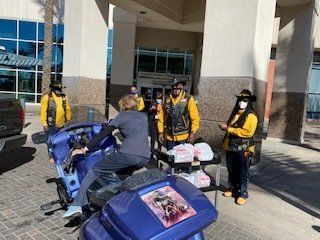 Motorcycle riders in yellow vests deliver food to a hospital.
