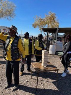 People in yellow vests at an outdoor event with a Jenga game on a table.