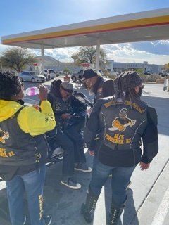 Group of people in biker vests at a Shell gas station.